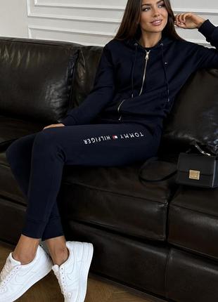 Женский спортивный костюм бренда tommy hilfiger, состоящий из худи на молнии и брюк.
