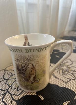 Ця порцелянова чашка бренду queen's із колекції beatrix potter зображує персонажа бенджаміна банні