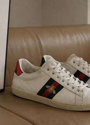 Кожаные кеды gucci ace из белой кожи с вышивкой в виде золотистой пчелы.