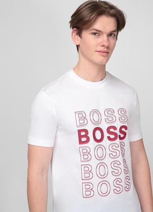 На даному зображенні показано чоловічу білу футболку бренду hugo boss з унікальним геометричним принтом.
