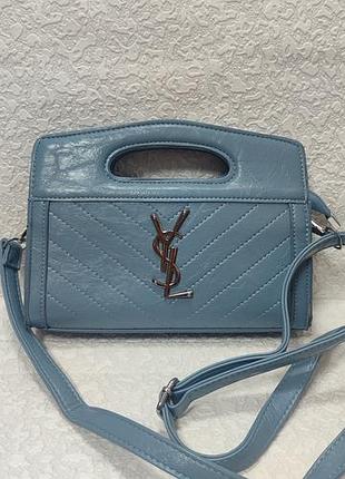 Женская сумка от бренда saint laurent (ysl), выполненная в голубом цвете из стеганой кожи с характерным металлическим логотипом ysl на передней панели