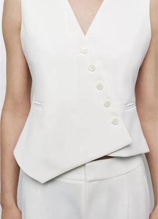 Білий жилет zara вирізняється асиметричним кроєм та застібкою на ґудзики