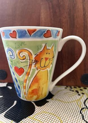 Керамічна чашка бренду rayware з яскравим ілюстрованим дизайном котів та сердець.