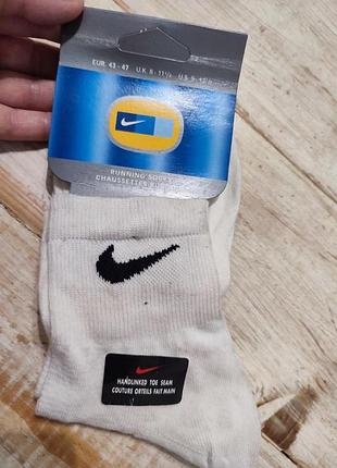 Белые спортивные носки nike с черным логотипом , предназначенные для бега.