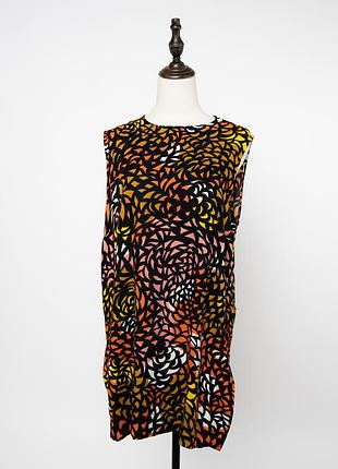 Яскрава сукня marimekko gita з ефектним, квітковим візерунком у помаранчевих, жовтих, рожевих та чорних відтінках. модель без рукавів має прямий