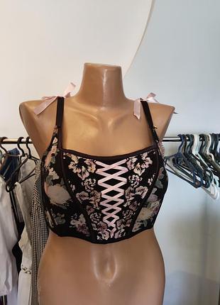 Черный корсетный топ от primark украшен цветочным узором и розовой шнуровкой спереди.