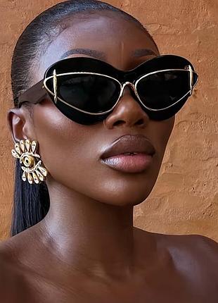 Жіночі сонцезахисні окуляри в стилі cat eye — ефектна модель у чорному кольорі з золотистим металевим контуром та темними лінзами.