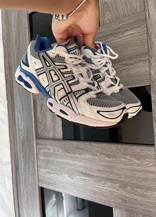 Кросівки asics gel-nimbus 9 у білому кольорі з синіми та сріблястими акцентами.