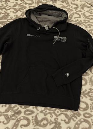 Чоловічій чорний худі є колаборацією alpha industries та new era, прикрашену логотипами команди raiders. розмір xl
