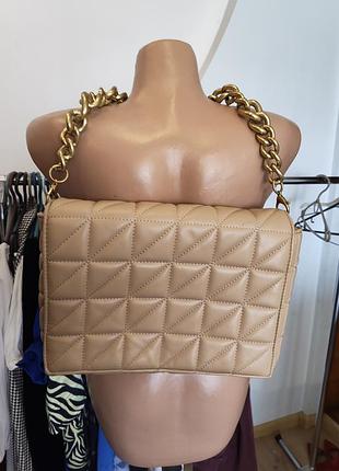 Бежевая стеганая сумка zara имеет характерную массивную золотая цепочка.