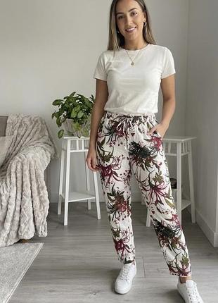 Жіночі брюки від бренду vero moda вирізняються яскравим тропічним принтом на білому фоні
