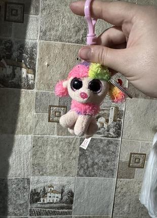 Цей брелок — ty beanie boos rainbow the poodle, що відрізняється яскравим багатобарвним хутром та великими блискучими очима