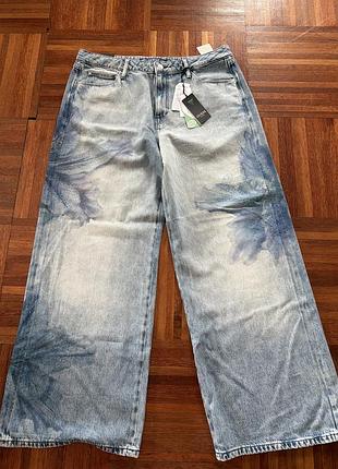 Широкі джинси guess eco bellflower printed wide-leg  блакитного кольоріу зі світлим вибіленим ефектом твеликим акварельно-квітковим принтом 34/32