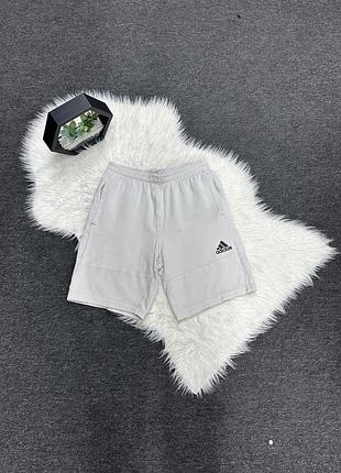Чоловічі шорти adidas світло-сірого кольору мають чорний логотип на лівій штанині.