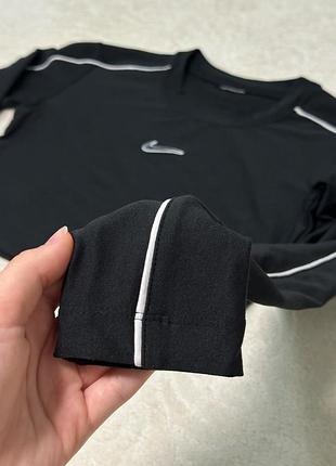 Чорний жіночий кроп-топ nike з довгими рукавами має білі смуги вздовж плечей