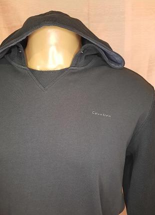 Чоловіче темно-сіре худі calvin klein з контрастною текстурною вставкою спереду та фірмовим логотипом.