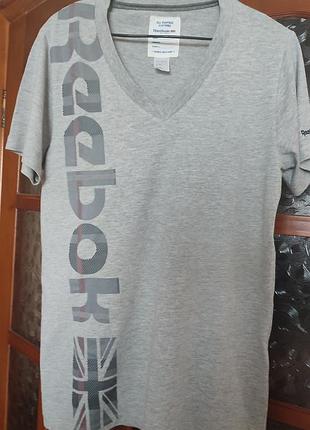 Оригинальная мужская футболка reebok classic с v-образным вырезом, серого цвета меланж. особенность модели — крупный вертикальный принт "reebok"