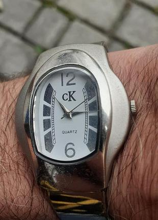 Винтажные кварцевые наручные часы марки calvin klein с овальным корпусом серебряного цвета и браслетом-сеткой.