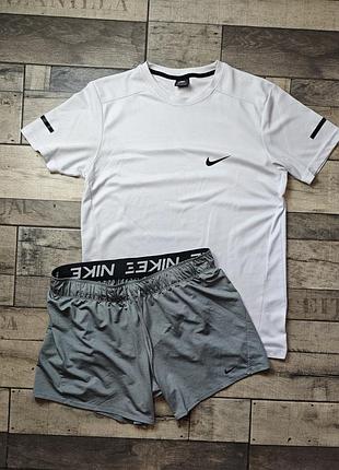Мужской спортивный комплект одежды nike включает белую футболку с логотипом на груди и серые шорты с брендингом на поясе. размер l