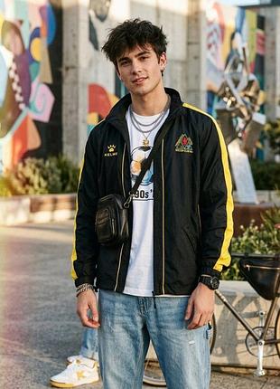 Ветровка бренда kelme с вышивкой.
и сеткой в средние.карманы на молнии.капюшон спрятан.