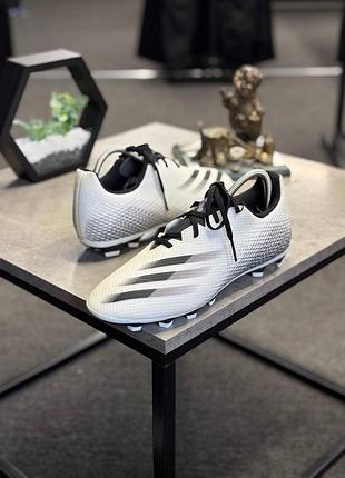 Бутси adidas x ghosted.4 fxg, виконані в білому кольорі з чорними акцентами.