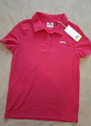 Жіноча футболка-поло slazenger pique polo shirt bright pink у яскраво-рожевому (фуксія) кольорі з фірмовим вишитим білим логотипом бренду на грудях.
