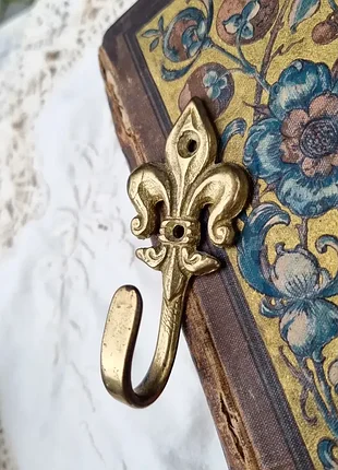Старинный крючок из бронзы в форме изображения французской лилии (fleur-de-lis).