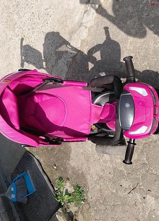 Дитячий триколісний велосипед-коляску (найімовірніше, модель turbo trike або tilly cayman) з батьківською ручкою та яскраво-рожевим капюшоном.основні