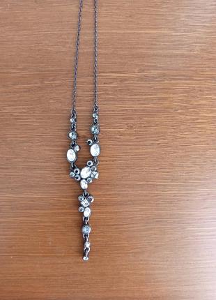 Це вінтажне  кольє  swarovski  моделі    diva  з кристалами  сірого та білого кольорів . довжина- 54, доп.ланцюжок -
7 см .виконане в чорному металі