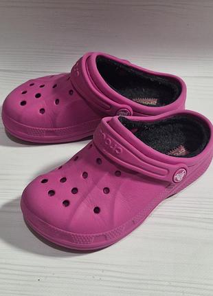 Детские утепленные сабо crocs ярко-розового цвета (колеру фуксии) с черной меховой подкладкой.