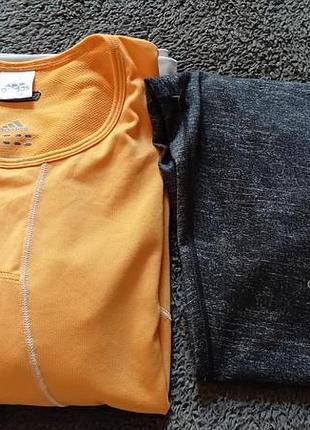 Комплект спортивного одягу adidas включає помаранчеву футболку та сірі легінси велосипедки.