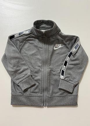 Сіра дитяча спортивна куртка nike має фірмову стрічку з логотипом на рукавах