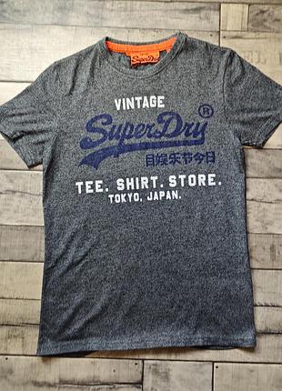 Чоловіча сіра футболка superdry vintage має характерний синій логотип на грудях і жовтогарячу обробку коміра розмір s