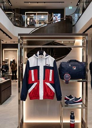 Пуховик бренда fila с ярким принтом с капюшоном и множеством карманов( из нюансов отсутствие снизу резинок )