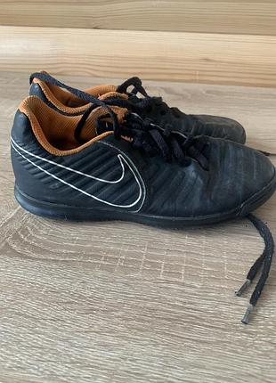 Дитячі футзалки nike tiempo legend 7 club з характерним чорним верхом і помаранчевою підкладкою.