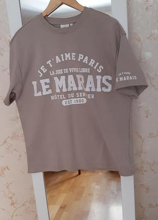 Бежевая футболка от only carmakoma выполнена в стиле оверсайз с графическим принтом le marais на груди.