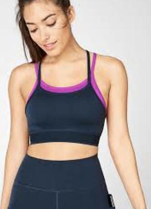 Спортивний топ — модель fabletics poppy, що вирізняється двошаровим дизайном із яскравою рожевою підкладкою та темно-синім зовнішнім шаром