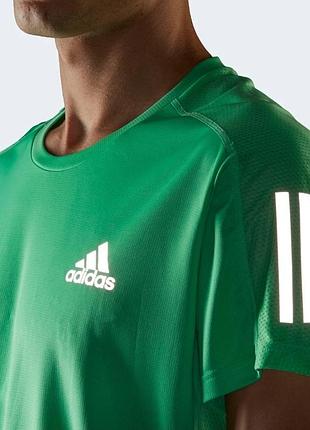 Зелена спортивна футболка adidas з фірмовими білими смужками на рукавах.