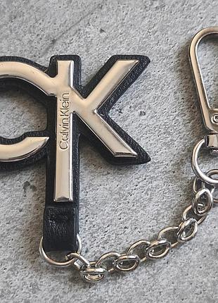 Брелок calvin klein с металлическим логотипом "ck" и кожаными элементами.