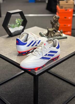 Футбольні бутси adidas copa pure 2 league у білому кольорі з синіми та червоними деталями.