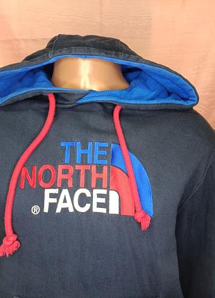 Темно-синє худі the north face з контрастним синьо-червоним вишитим логотипом на грудях і яскраво-червоними шнурками.