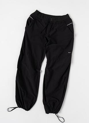 Жіночі, спортивні штани nike vintage 00s чорного кольору. виконані з легкого нейлону, мають еластичний пояс із шнурком для регулювання посадки, зручні