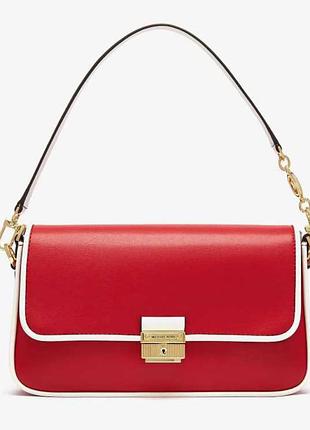 Це маленька оригінальна шкіряна сумка через плече michael kors bradshaw у червоному кольорі з білим кантом.
