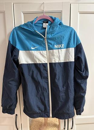 Вітровка nike у синьо-блакитних тонах із білою смугою на грудях.