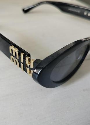 Солнцезащитные очки miu miu модели 11ws с черной ацетатной оправой и золотистым логотипом на скобках.