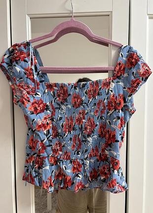 Топ від zara має синій колір із яскравим квітковим принтом та еластичною вставкою на грудях.