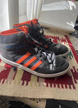 Дитячі кросівки adidas hoops mid мають темно-сірий замшевий верх із яскраво-помаранчевими смужками.