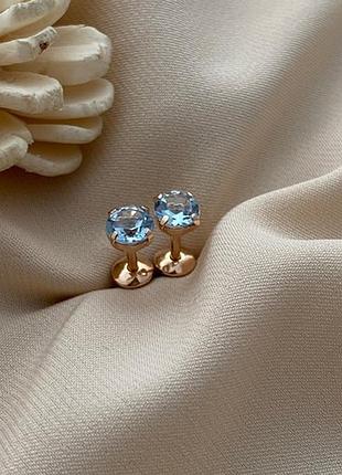 Серьги вкрутки золотые с круглыми голубыми топазами.