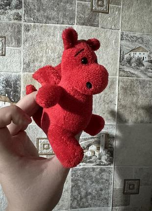М'яка іграшка — червоний валлійський дракон (символ уельсу, y ddraig goch), виконана з яскраво-червоного плюшу з невеликими крильцями на спині.