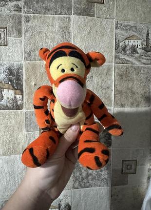 Плюшева іграшка тигра (tigger) від бренду disney  про вінні-пуха, яка має помаранчеве забарвлення з чорними смугами та характерни